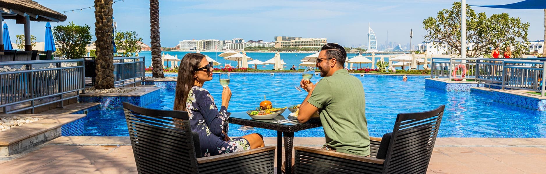 Guests dining poolside at Riva Beach Club