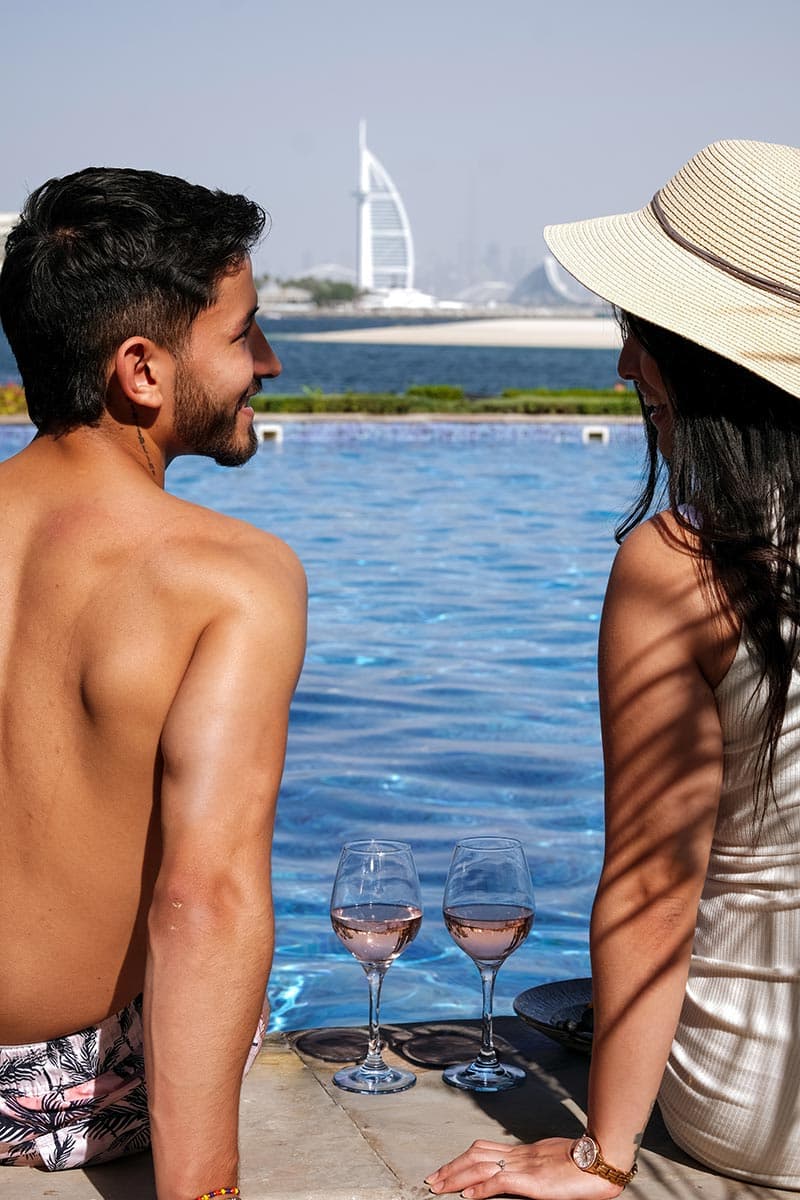Beach club guests gathered around a poolside table at Riva