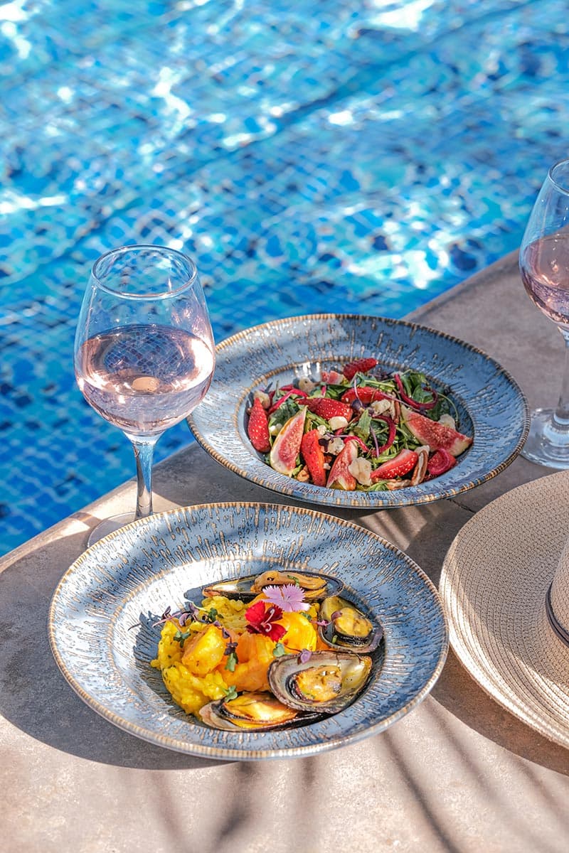 Guests relaxing near the pool with refreshments at Riva